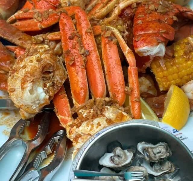 Snow crab legs, a lobster tail and corn from the boil, with a bowl of raw oysters at Stinkin' Crawfish